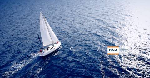 Een boot op zee met het logo van DNA Yachtinsurance